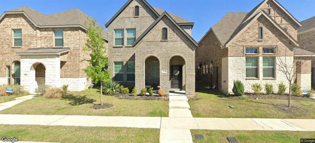 4129 Bullwhip Creek Lane, Sachse, TX 75048 Two-story brick and stone facade residence featuring arched entryways, a dark paneled front door, and a concrete pathway