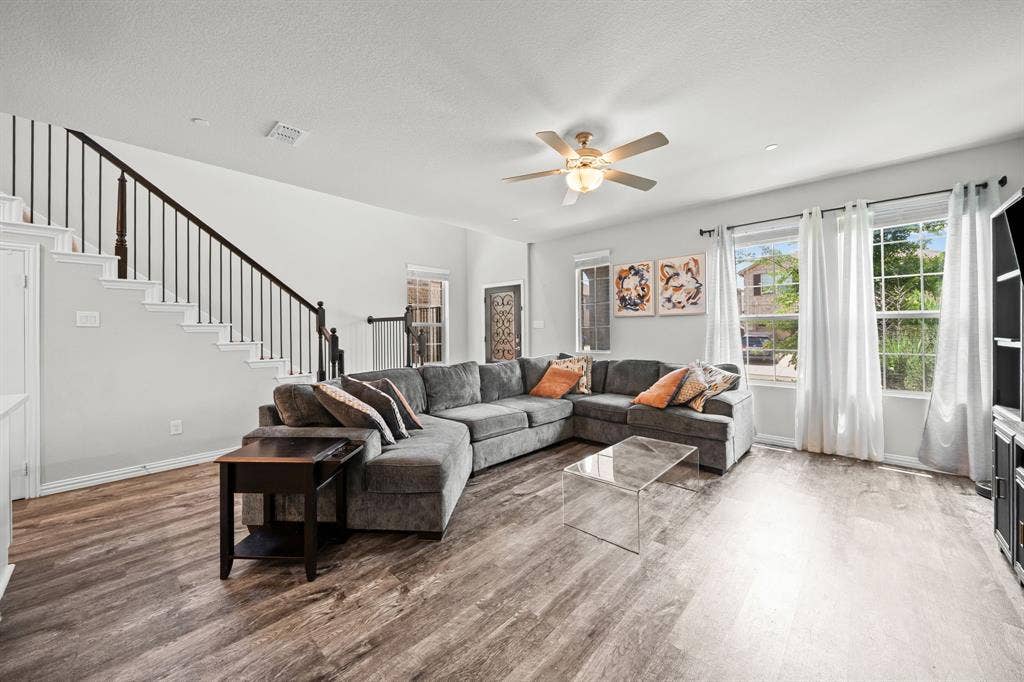 4129 Bullwhip Creek Lane, Sachse, TX 75048 Spacious living area featuring wood-finish flooring, a ceiling fan, and large windows