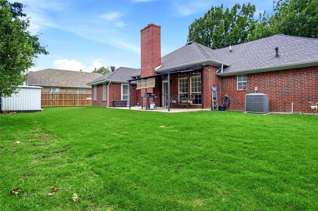 rear view of full brick home with brick chimney, 21x10 covered porch with 12 ft metal cover & metal shed