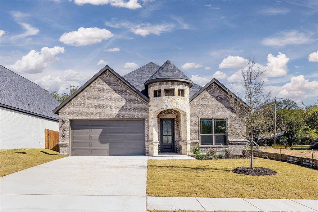 902 Boston Lane, River Oaks, TX 76114 Contemporary brick exterior featuring a stone turret entrance, dark-shingle roof, two-car garage, and a concrete driveway