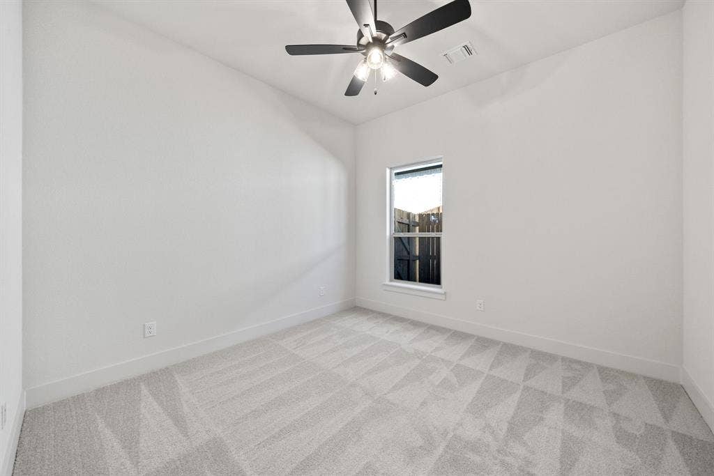 902 Boston Lane, River Oaks, TX 76114 Room featuring light gray patterned carpeting, a single window, white walls, and a ceiling fan with integrated lighting