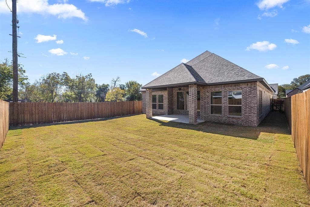 902 Boston Lane, River Oaks, TX 76114 Spacious backyard with a wood privacy fence, sodded lawn, and a covered concrete patio