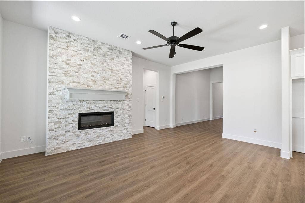 902 Boston Lane, River Oaks, TX 76114 Spacious living area featuring a stone accent wall with a fireplace, wood-finish flooring, recessed lighting, a ceiling fan, and built-in shelving