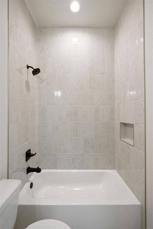 902 Boston Lane, River Oaks, TX 76114 Bathtub and shower combination featuring floor-to-ceiling rectangular tile surround, matte black fixtures, an integrated shower niche, and a recessed ceiling light