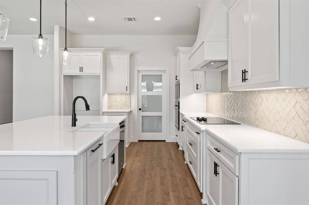 902 Boston Lane, River Oaks, TX 76114 Modern kitchen featuring white cabinetry, quartz countertops, a farmhouse sink with a black matte faucet, a herringbone tile backsplash, and wood-finish flooring