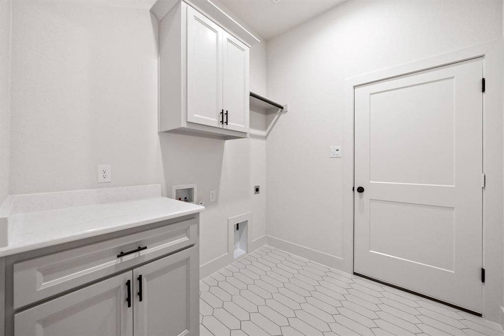 902 Boston Lane, River Oaks, TX 76114 Laundry area featuring white cabinetry with black hardware, a light-toned countertop, a built-in hanging rod, and geometric tile flooring