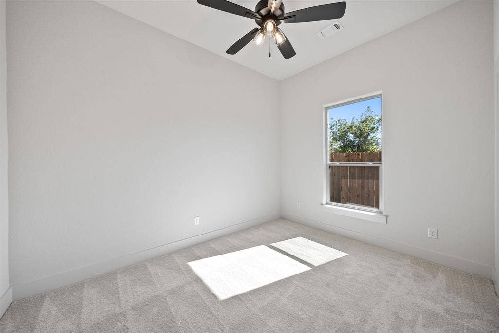 902 Boston Lane, River Oaks, TX 76114 Neutral-toned room featuring a single window, light gray carpeting, and a ceiling fan with integrated lighting