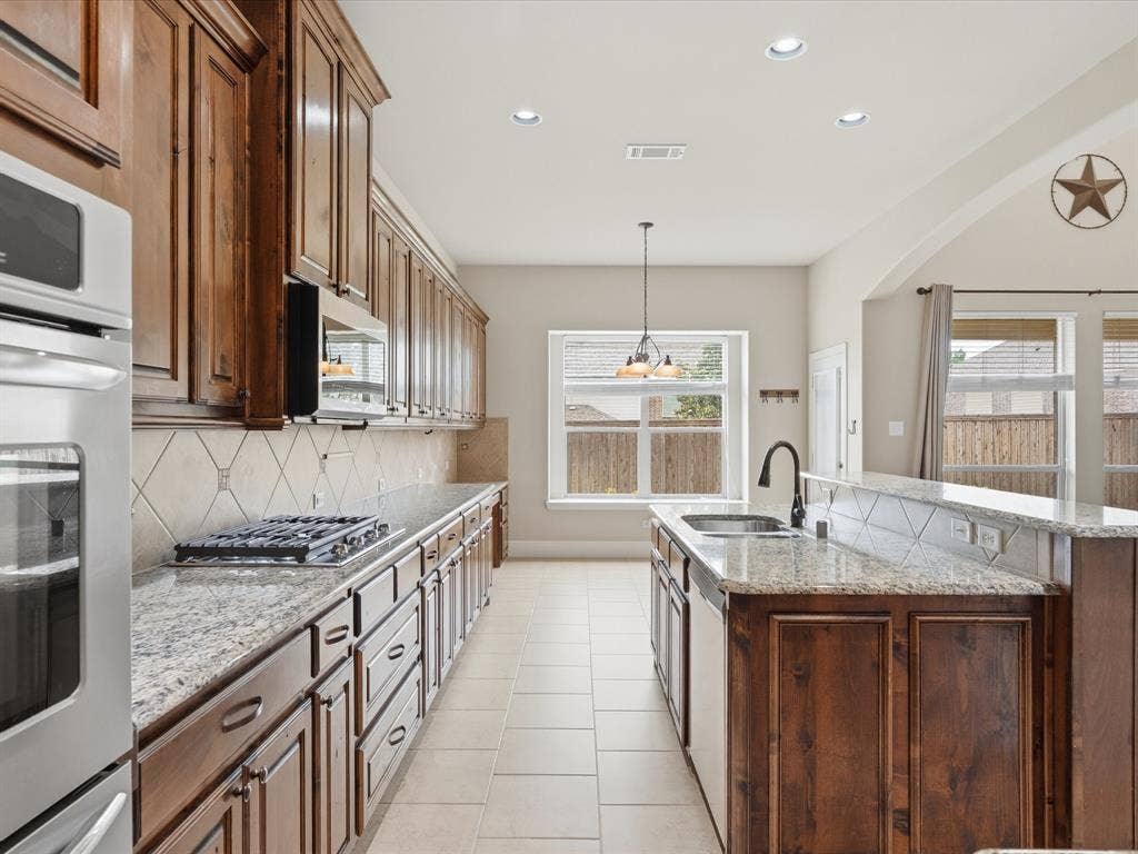 1621 Lakemere Drive, Prosper, TX 75078 Gourmet kitchen featuring a built-in oven, gas cooktop, rich wood cabinetry, granite countertops, and tile flooring