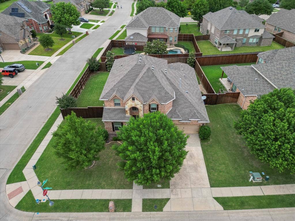 1621 Lakemere Drive, Prosper, TX 75078 Brick and stone exterior residence featuring a gabled roofline, mature front yard trees, a concrete driveway, and a fenced backyard