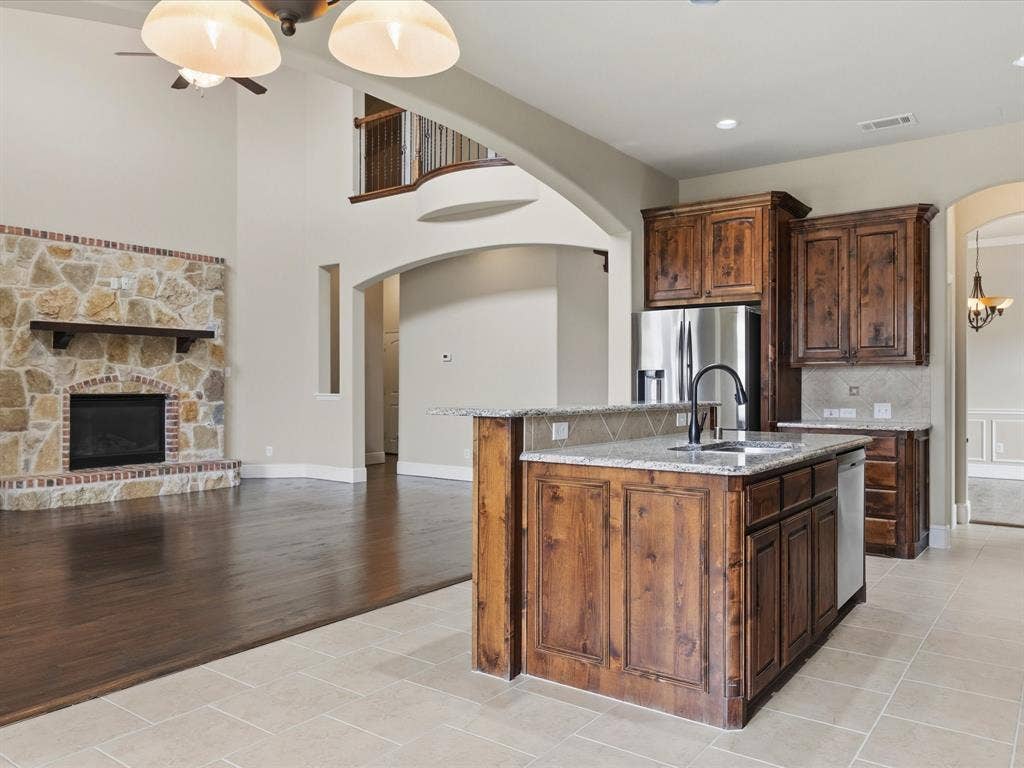 1621 Lakemere Drive, Prosper, TX 75078 Open-concept kitchen featuring an island with a double basin sink, stainless steel appliances, and wood cabinetry