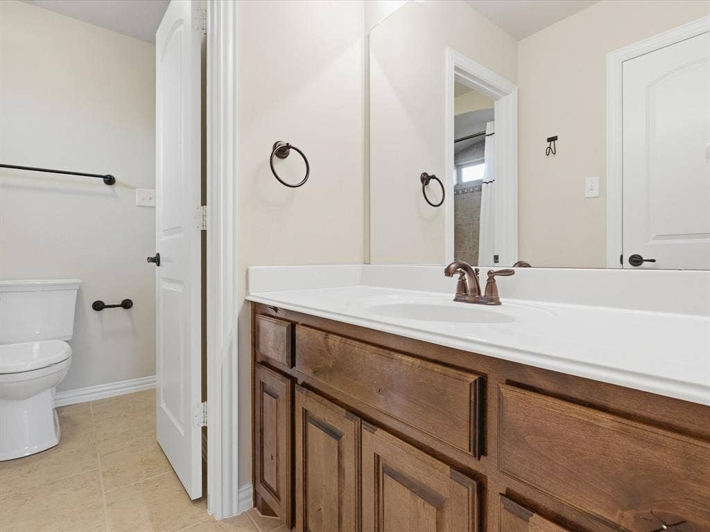 1621 Lakemere Drive, Prosper, TX 75078 Bathroom vanity with wood-finish cabinetry, a white countertop, and an integrated sink