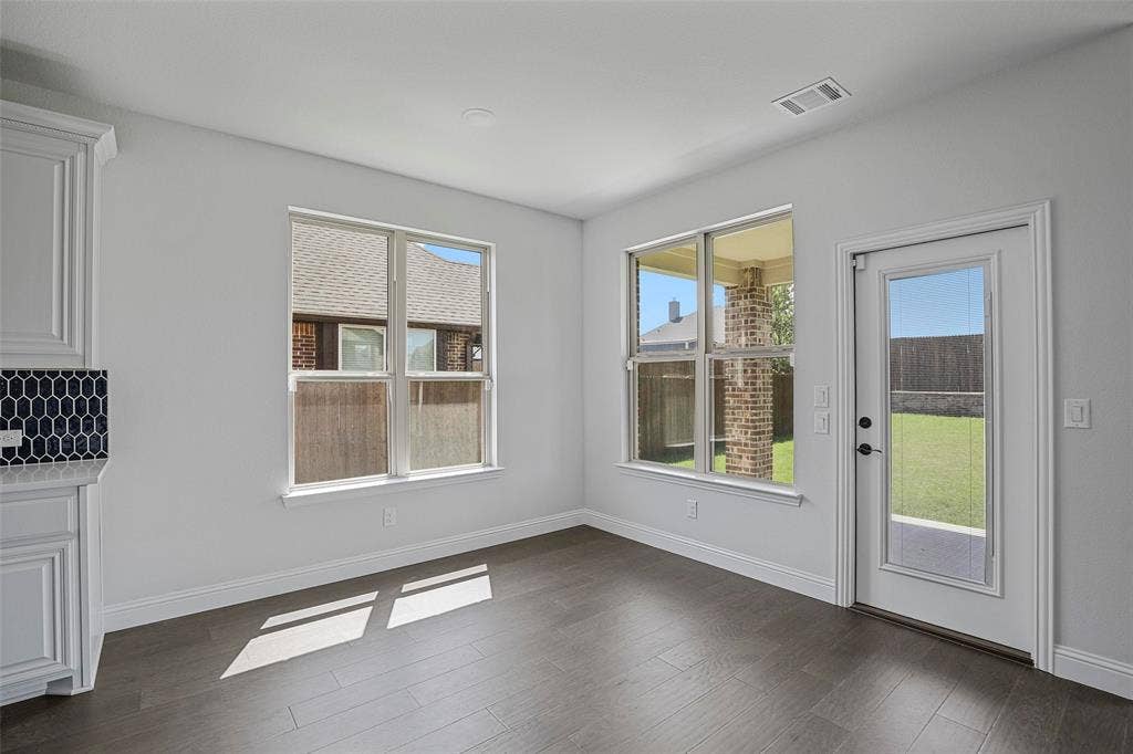 508 Bush Avenue, Waxahachie, TX 75165 Spacious room with dark wood-finish flooring, white walls, and a large window overlooking a covered patio