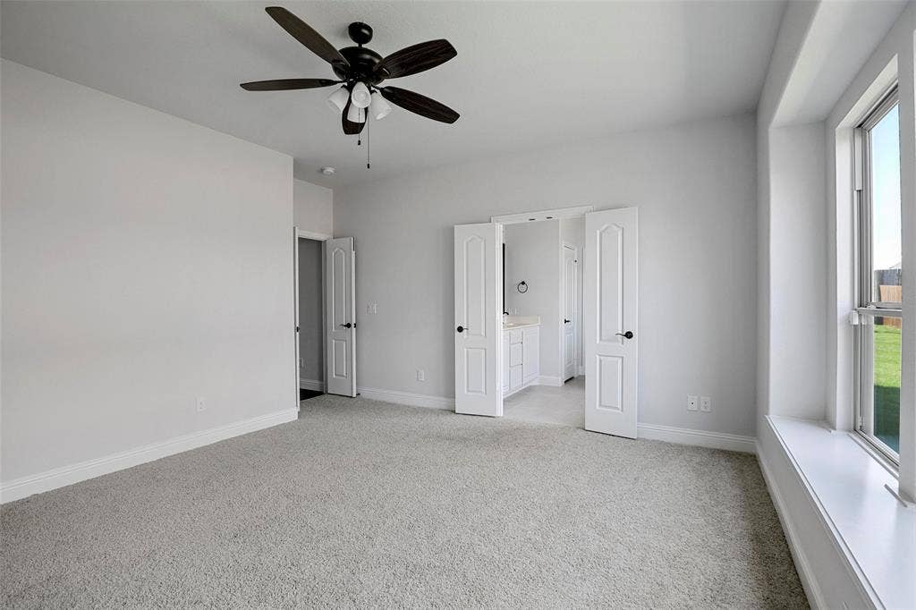 508 Bush Avenue, Waxahachie, TX 75165 Carpeted room with a ceiling fan, a window with a white sill, and two white doors with black hardware