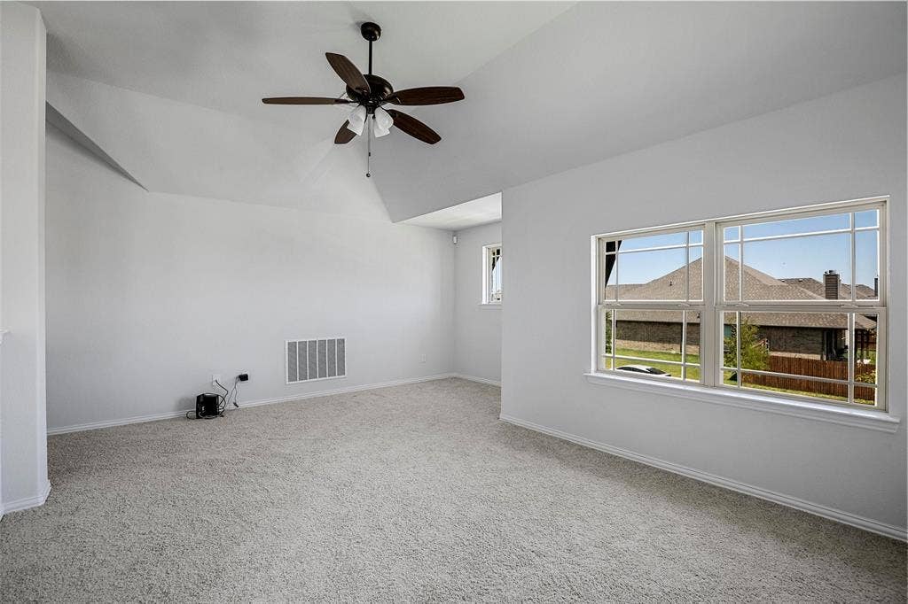 508 Bush Avenue, Waxahachie, TX 75165 Carpeted room featuring a ceiling fan, a vaulted ceiling, and multiple windows