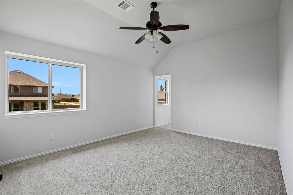 508 Bush Avenue, Waxahachie, TX 75165 Spacious room featuring vaulted ceilings, a ceiling fan with integrated lighting, soft gray carpeting, and multiple windows providing natural light