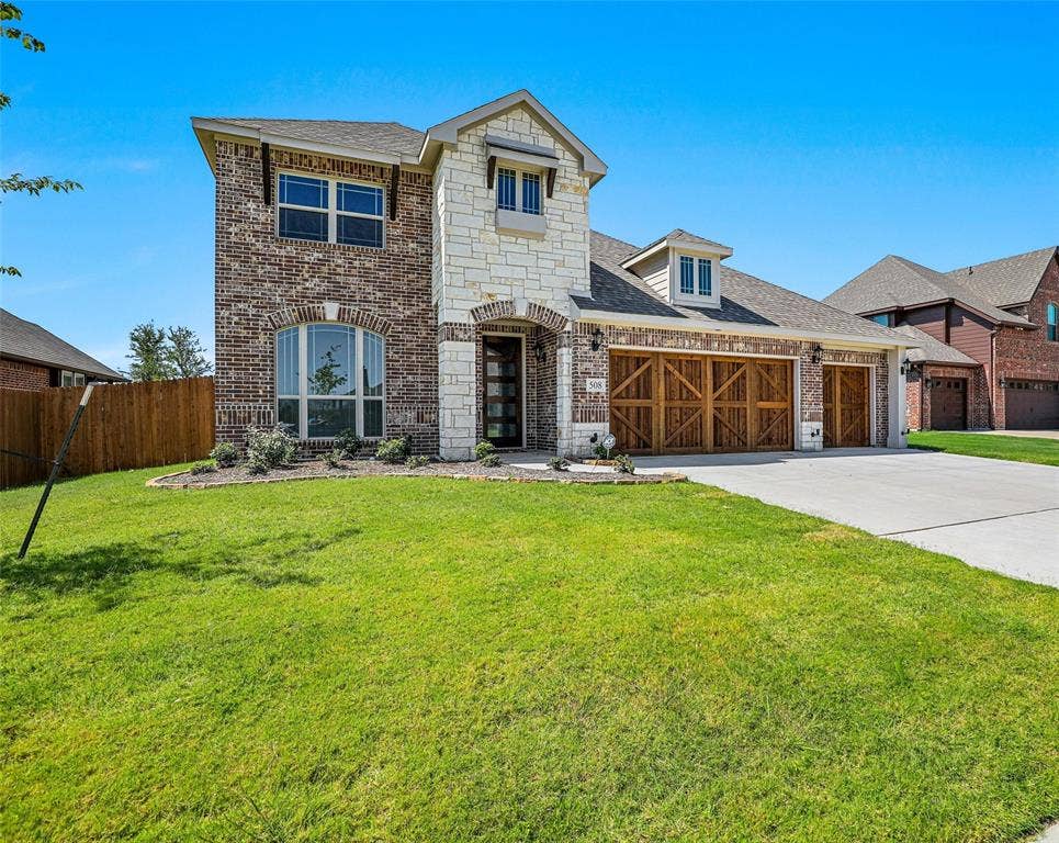 508 Bush Avenue, Waxahachie, TX 75165 Two-story residence featuring a brick and stone facade, arched entryway, and a three-car garage with wood-finish doors
