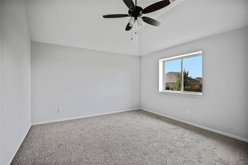 508 Bush Avenue, Waxahachie, TX 75165 Spacious room featuring neutral carpeting, light gray walls, a contemporary ceiling fan, a vaulted ceiling, and a large window