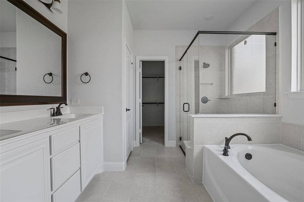 508 Bush Avenue, Waxahachie, TX 75165 Bathroom featuring a dual vanity with white cabinetry, a built-in soaking tub, a glass-enclosed shower, and a walk-in closet