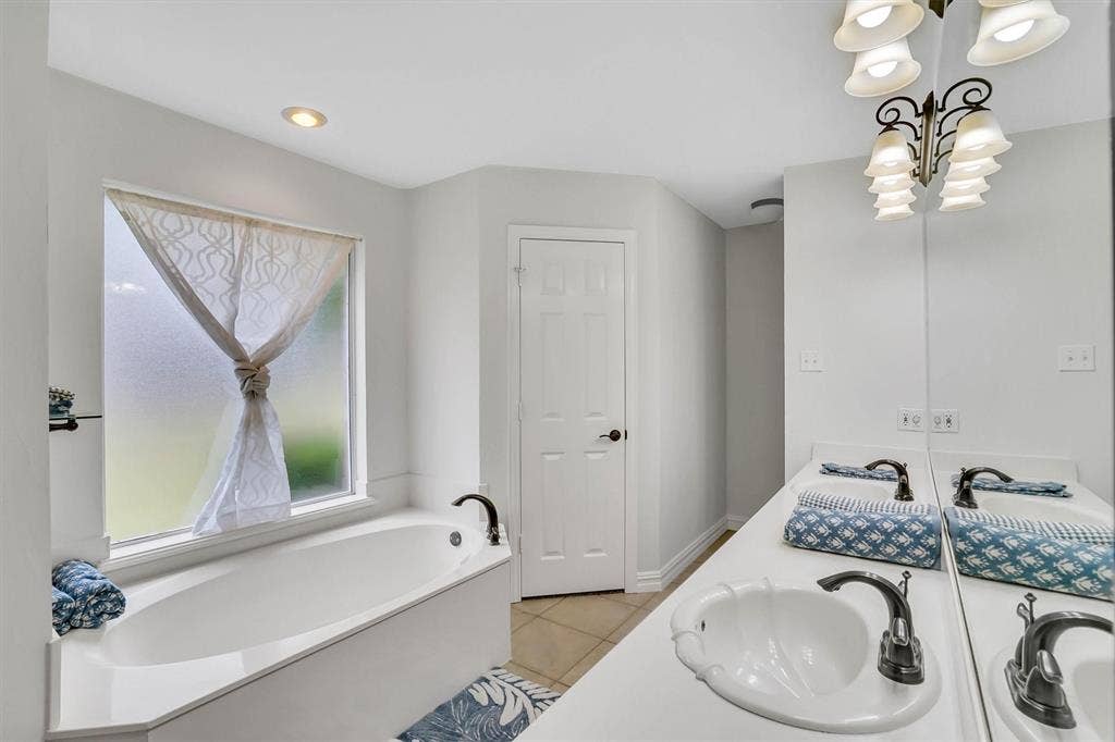 428 Shelby Drive, Burleson, TX 76028 White soaking tub with dark bronze fixtures, set against a frosted window