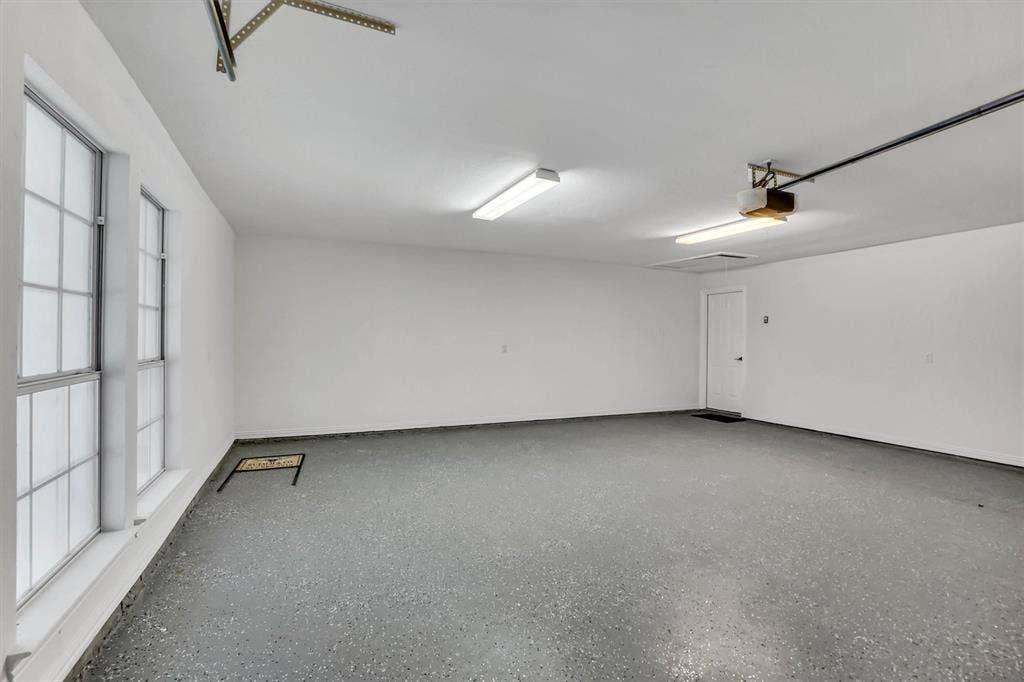 428 Shelby Drive, Burleson, TX 76028 Spacious garage featuring a durable speckled epoxy floor, white painted walls, and ample natural light from two multi-pane windows