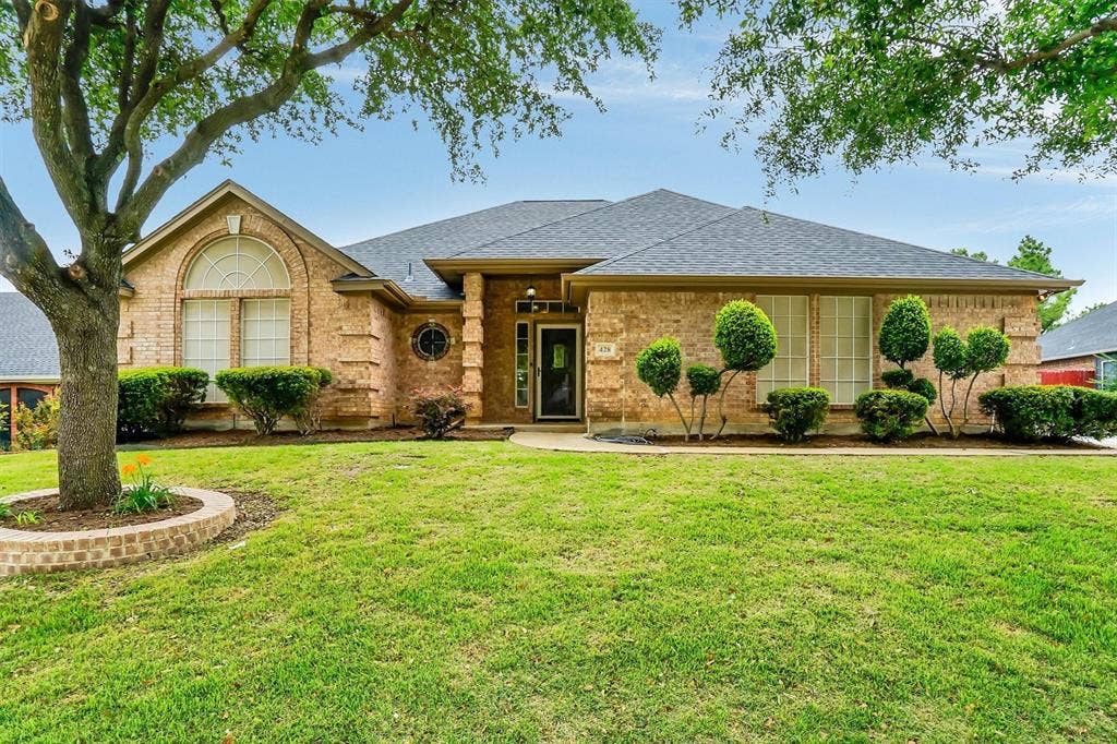 428 Shelby Drive, Burleson, TX 76028 Brick exterior featuring a gabled roofline, arched window, circular accent window, and mature landscaping