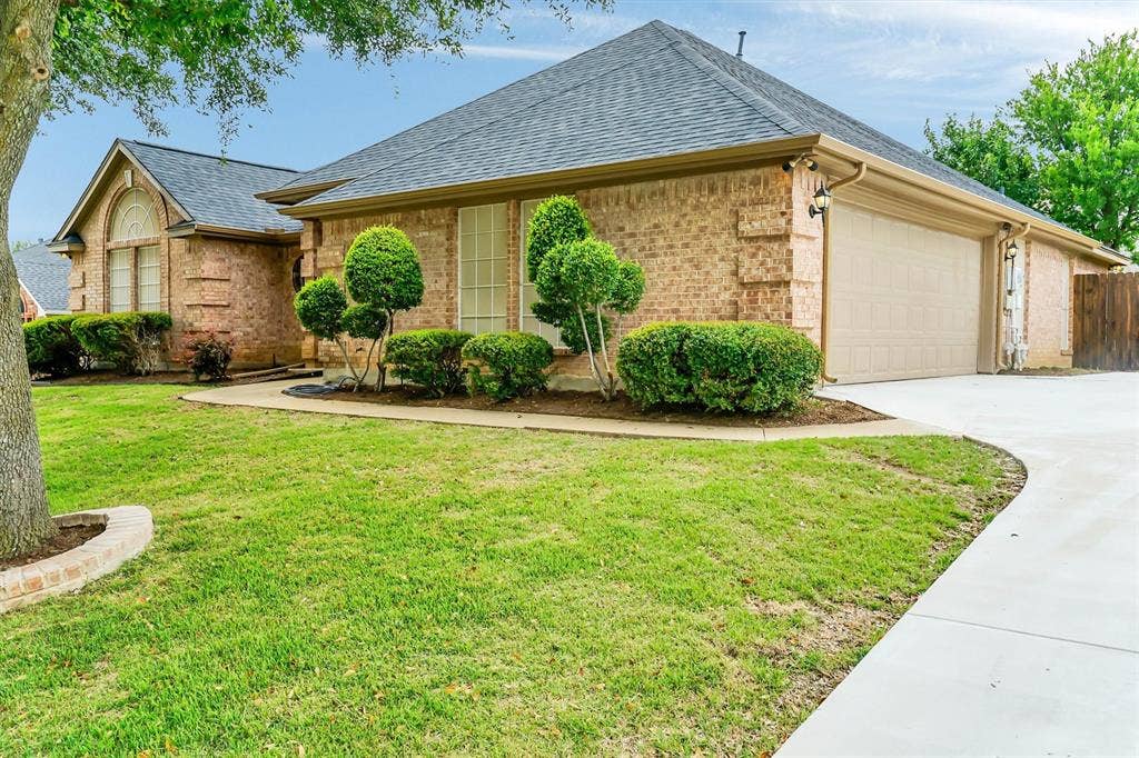 428 Shelby Drive, Burleson, TX 76028 Traditional brick exterior featuring a multi-gabled roofline, an attached two-car garage, and a curved concrete driveway