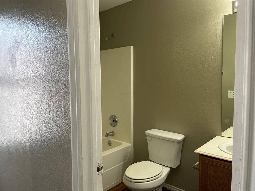 817 Greene Way, Wylie, TX 75098 Bathroom featuring a built-in tub with shower, single vanity with a laminate countertop, and a wall-mounted mirror