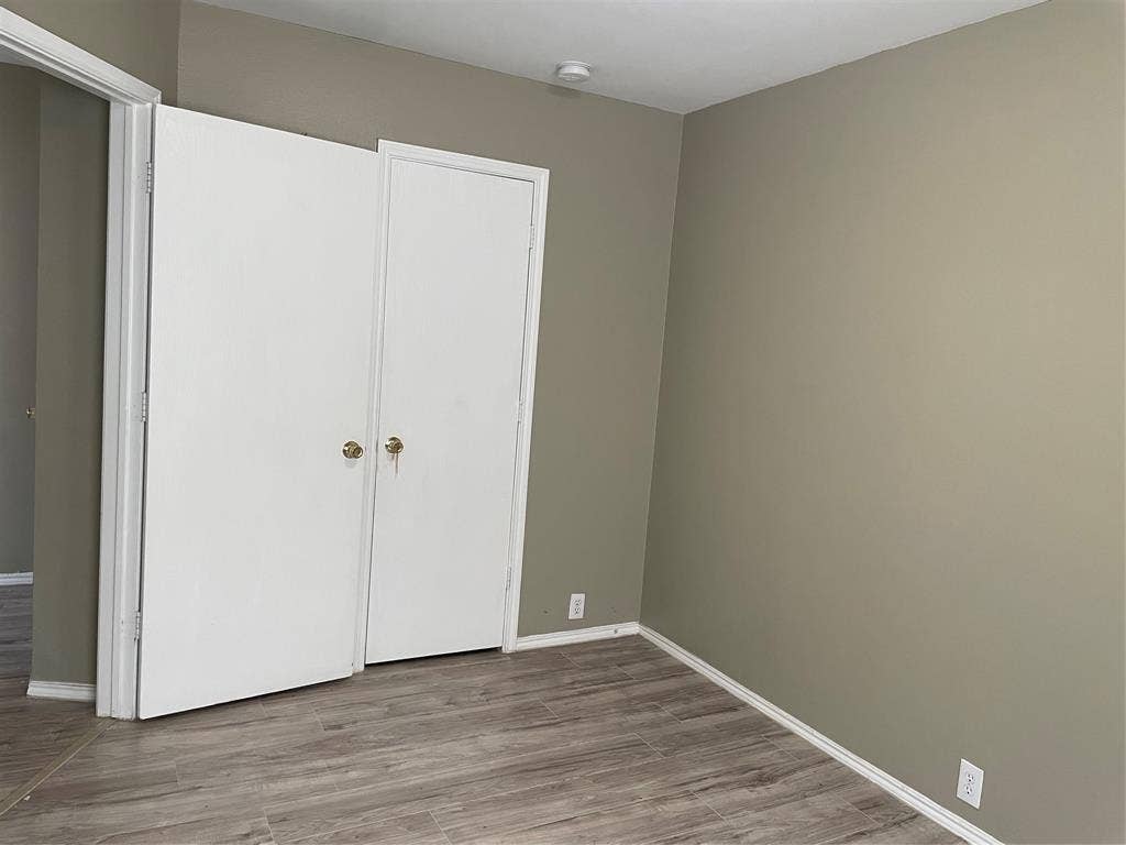 817 Greene Way, Wylie, TX 75098 Room featuring wood-finish flooring, neutral wall paint, white baseboards, and a white bi-fold closet