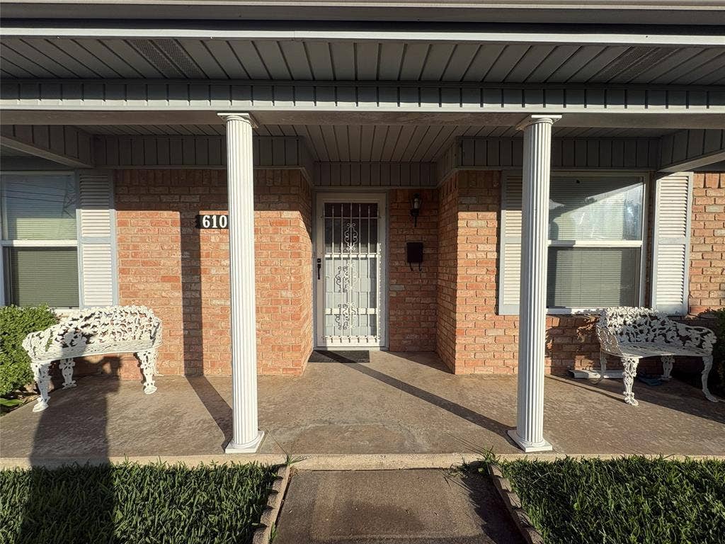 6100 Landmark Drive, Waco, TX 76710 Brick exterior featuring a covered porch with two fluted columns, a concrete slab, and an address marker