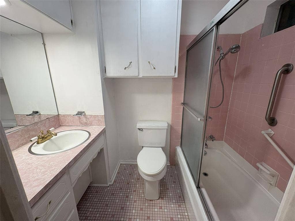 6100 Landmark Drive, Waco, TX 76710 Bathroom featuring a full vanity with an integrated sink, a toilet, an enclosed shower-tub combination, and tiled flooring