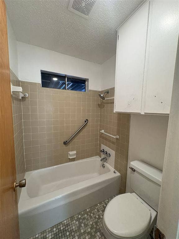 6100 Landmark Drive, Waco, TX 76710 Bathroom featuring a white bathtub, beige tile surround, mosaic tile flooring, and a window