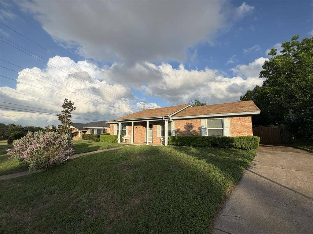 6100 Landmark Drive, Waco, TX 76710 Brick exterior residence featuring a brown shingle roof, established front lawn, manicured hedges, and a paved driveway