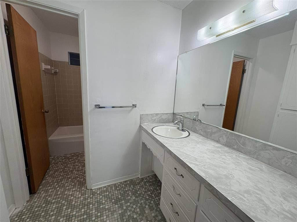 6100 Landmark Drive, Waco, TX 76710 Bathroom featuring a long vanity with an integrated sink, patterned countertop, and full-width mirror