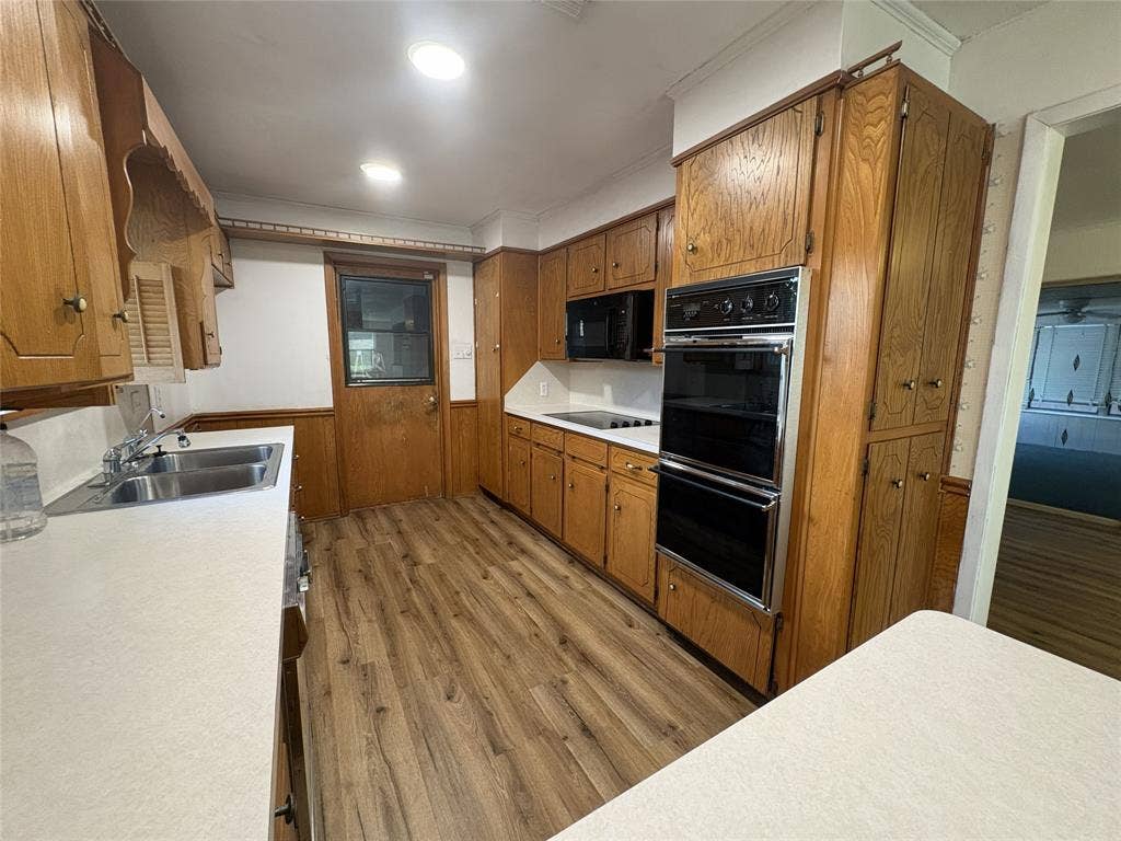 6100 Landmark Drive, Waco, TX 76710 Kitchen featuring wood-finish flooring, ample cabinetry, double wall ovens, a built-in microwave, and solid surface countertops