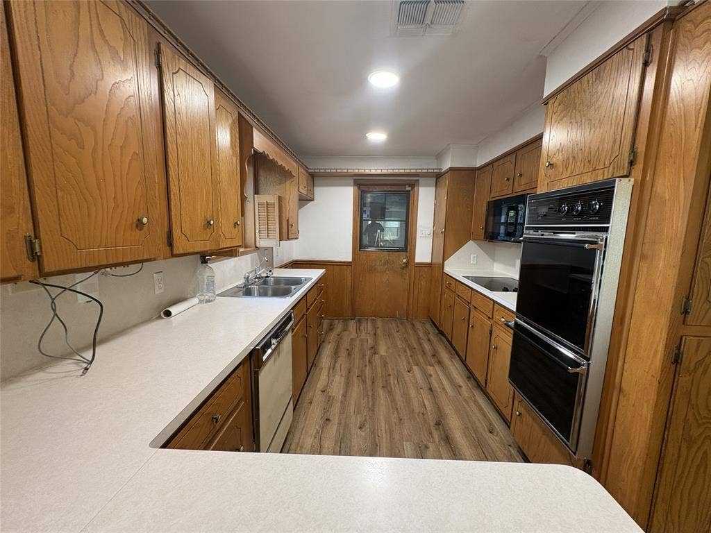 6100 Landmark Drive, Waco, TX 76710 Kitchen with wood-finish cabinetry, light countertops, wood-finish flooring, and a built-in double oven