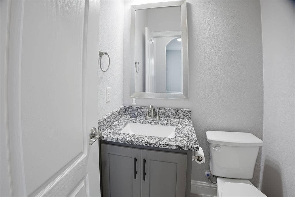 620 Shadow Trail, Frisco, TX 75033 Bathroom featuring a gray vanity with black hardware, a granite-finish countertop, an undermount sink, and a framed mirror
