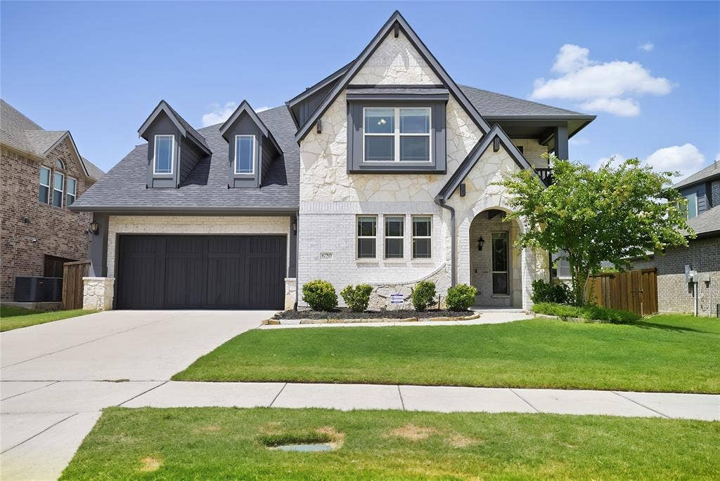 620 Shadow Trail, Frisco, TX 75033 Two-story residence featuring a stone and brick facade, dark gray gabled roof, and twin dormer windows