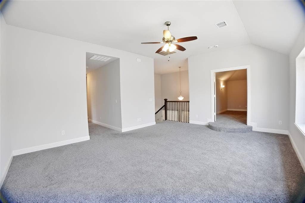 620 Shadow Trail, Frisco, TX 75033 Spacious carpeted room featuring vaulted ceilings, a ceiling fan with integrated lighting, a raised entry to an interior room, and a staircase with wood newel posts and railings