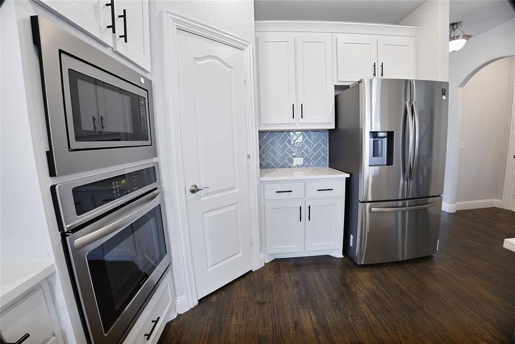 620 Shadow Trail, Frisco, TX 75033 Kitchen featuring stainless steel appliances, white cabinetry with dark hardware, a herringbone pattern tile backsplash, and wood-finish flooring