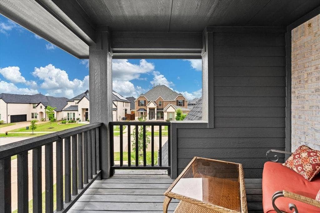 620 Shadow Trail, Frisco, TX 75033 Covered porch featuring dark wood-finish decking and railing, dark horizontal siding, and a light-colored brick wall