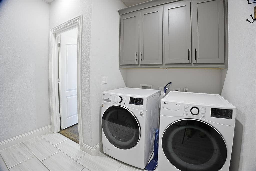 620 Shadow Trail, Frisco, TX 75033 Laundry room featuring light gray wall cabinets with dark hardware, white walls, and light-toned tile flooring
