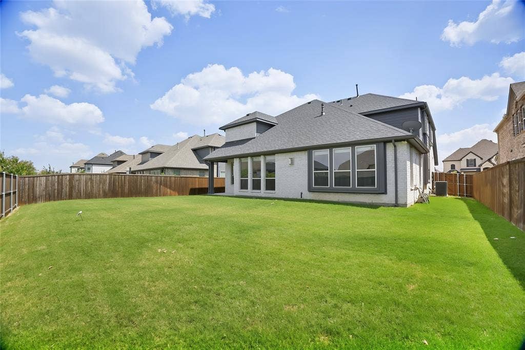 620 Shadow Trail, Frisco, TX 75033 Expansive backyard featuring a lush lawn, privacy fencing, and a white brick exterior with dark trim