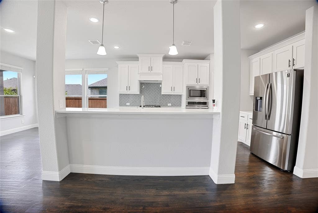 620 Shadow Trail, Frisco, TX 75033 Modern kitchen featuring white shaker cabinetry, stainless steel appliances, a breakfast bar, recessed lighting, and wood-finish flooring