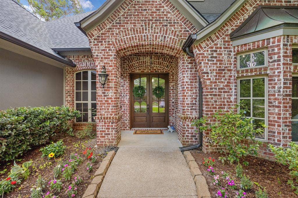 1915 Stonegate Valley Drive, Tyler, TX 75703 Brick and stucco exterior with an arched entryway and double glass-paneled doors