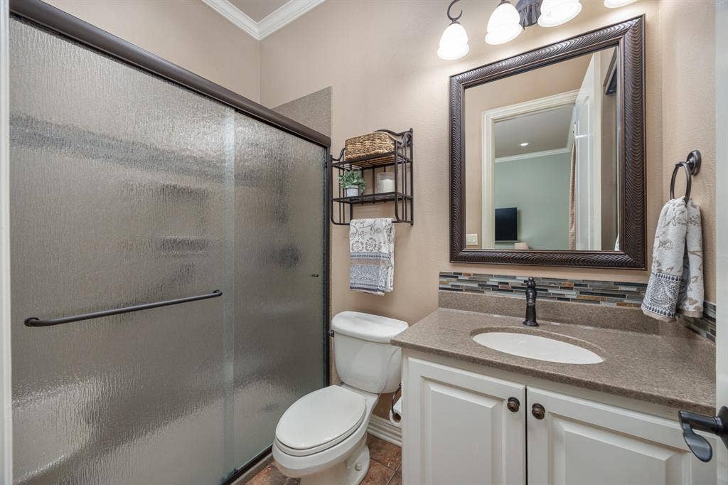 1915 Stonegate Valley Drive, Tyler, TX 75703 Bathroom featuring a textured glass shower enclosure and vanity with stone-finish countertop and a decorative tile backsplash