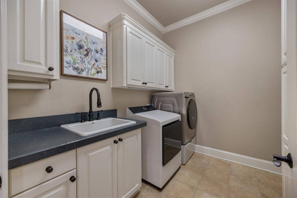 1915 Stonegate Valley Drive, Tyler, TX 75703 Utility room featuring a built-in sink, white cabinetry with dark hardware, dark countertop, and crown molding