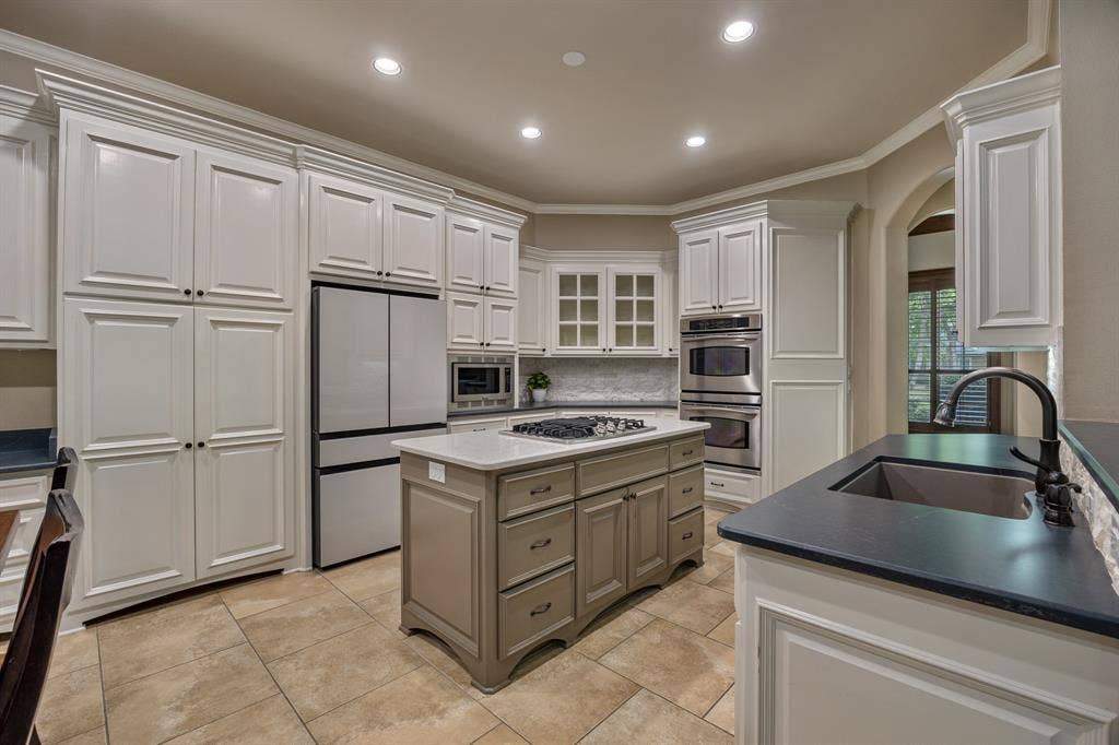 1915 Stonegate Valley Drive, Tyler, TX 75703 Spacious kitchen featuring white cabinetry, a center island with a gas cooktop, stainless steel appliances, dark countertops, and tiled flooring
