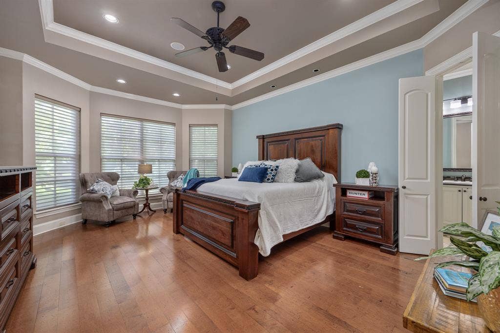 1915 Stonegate Valley Drive, Tyler, TX 75703 Spacious room featuring wood flooring, a tray ceiling with recessed lighting and a ceiling fan, and a large bay window with window treatments