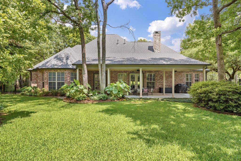 1915 Stonegate Valley Drive, Tyler, TX 75703 Expansive backyard featuring a manicured lawn, mature trees, and a covered patio