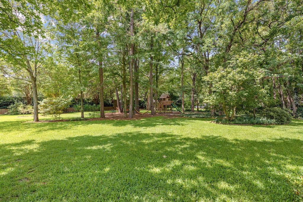 1915 Stonegate Valley Drive, Tyler, TX 75703 Expansive backyard featuring a lush lawn, mature trees providing natural shade, and dense perimeter landscaping